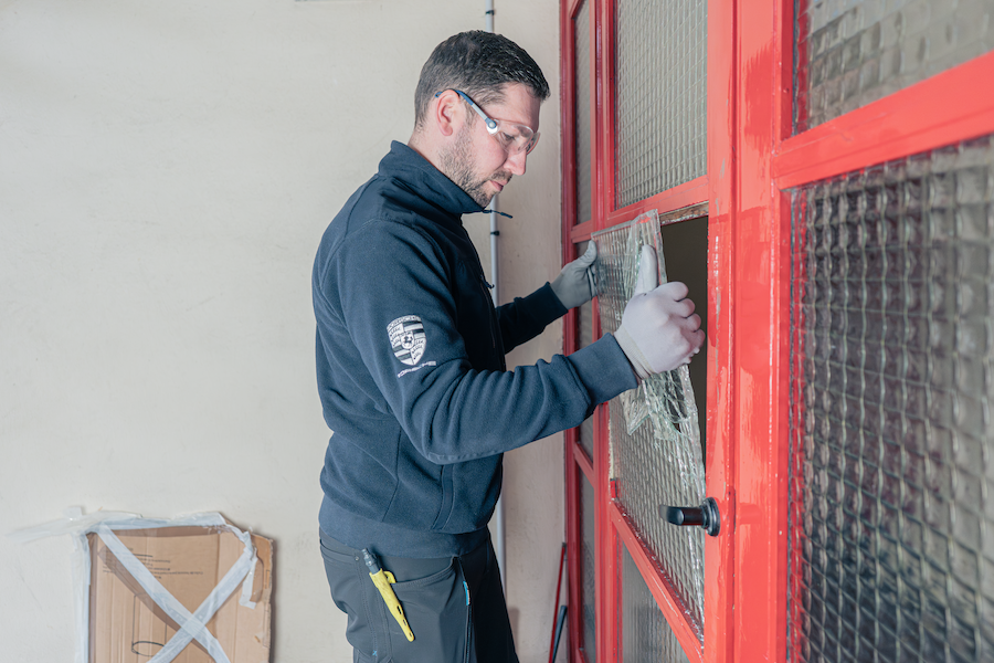 Technicien remplaçant une vitre cassée sur porte d’immeuble lors d’une intervention de serrurerie et sécurisation par Serrure Elec.